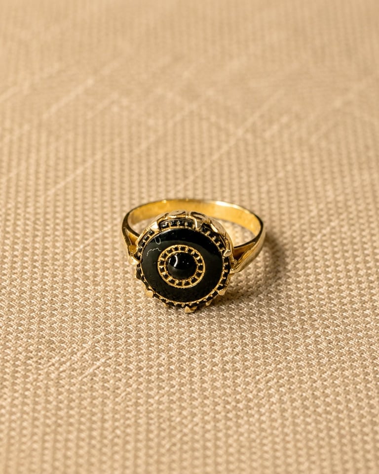 Gold-toned ring with black circular face and Roman numerals on beige textured fabric background