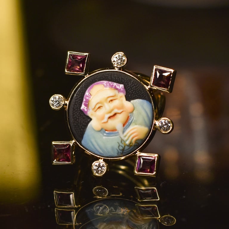 Gold pendant brooch featuring a portrait of a laughing baby on black enamel, surrounded by alternating round and square gemstones