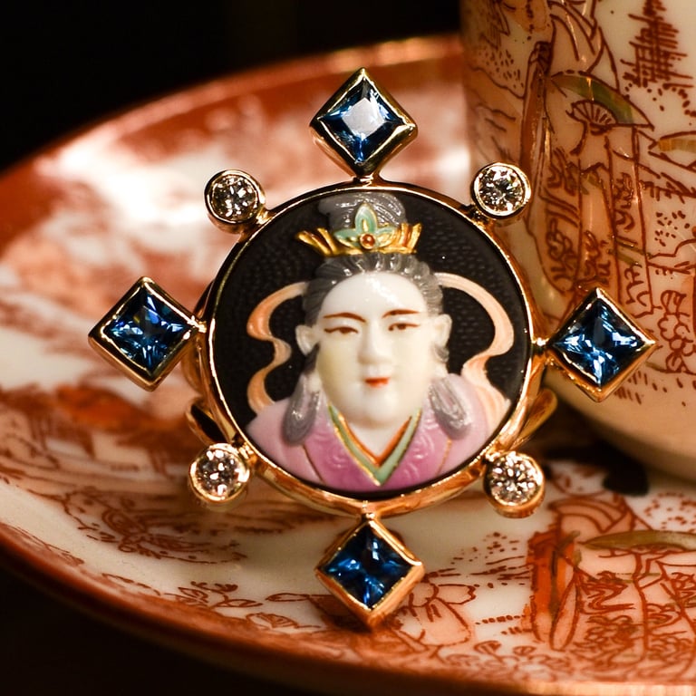 Ornate brooch with portrait of Asian woman, blue and clear gemstones, on decorative ceramic plate with red floral pattern