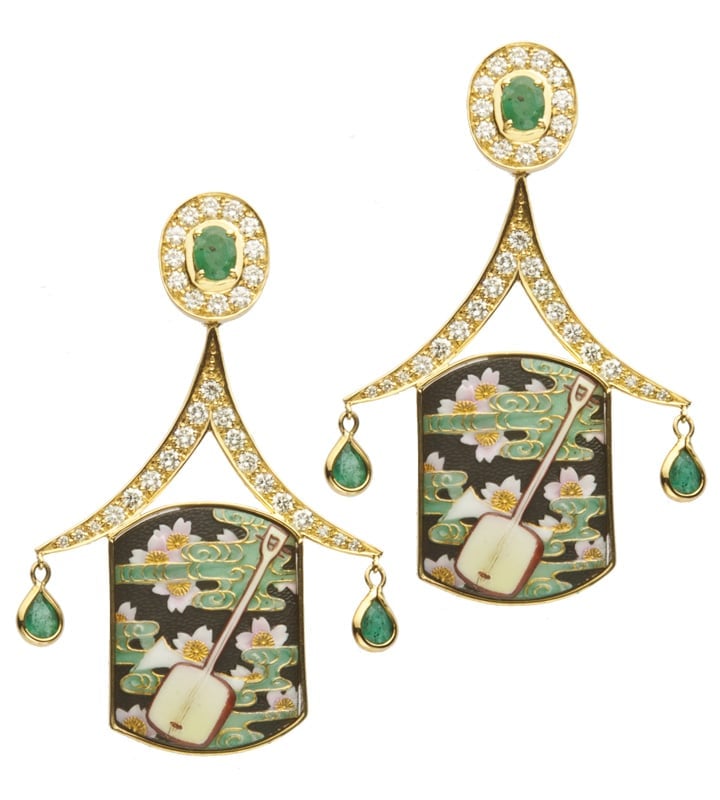 Pair of gold and emerald drop earrings with enamel plaques featuring water lilies and musical instruments, accompanied by hanging teardrop gemstones