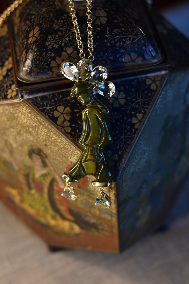Gold pendant necklace with flower charm and crystal accents displayed on ornate decorative boxes